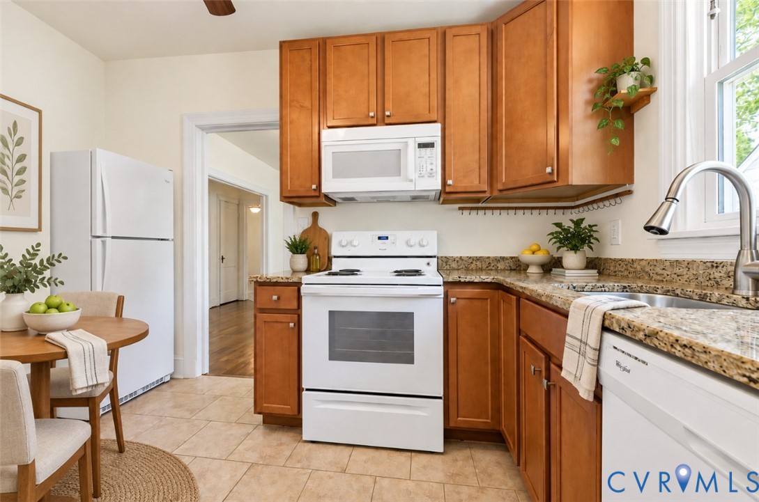 Wood-finish cabinetry paired with a granite-style countertop, featuring a stainless steel gooseneck faucet