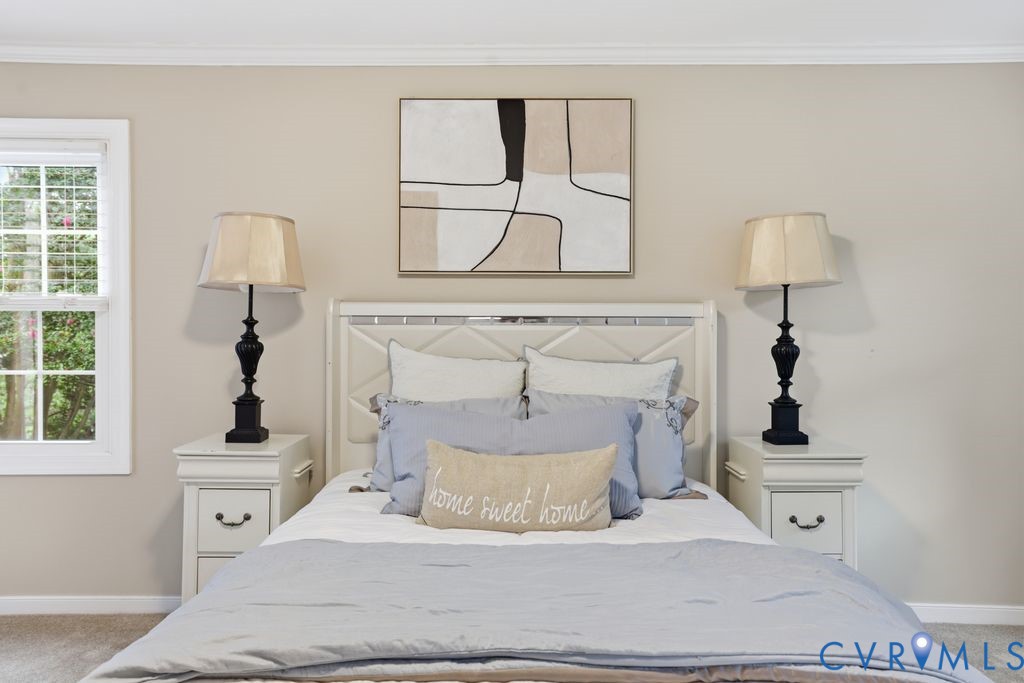 Bedroom featuring a white paneled headboard, matching white nightstands with drawer storage, and a double-hung window