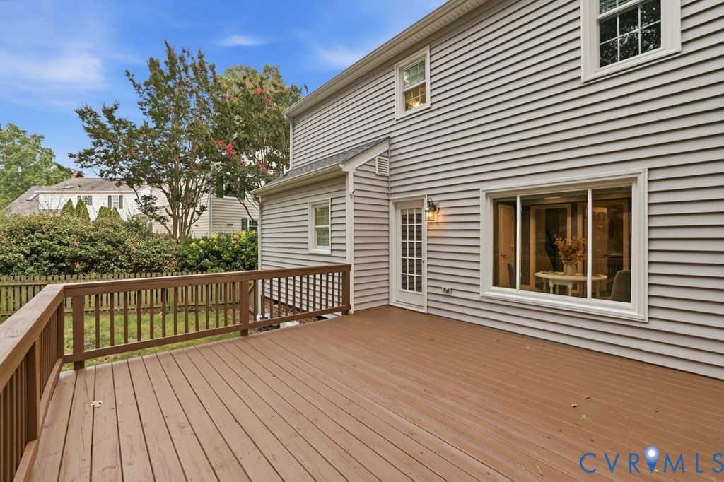 Expansive deck featuring warm wood-finish decking, horizontal railings with balusters, and integrated lighting