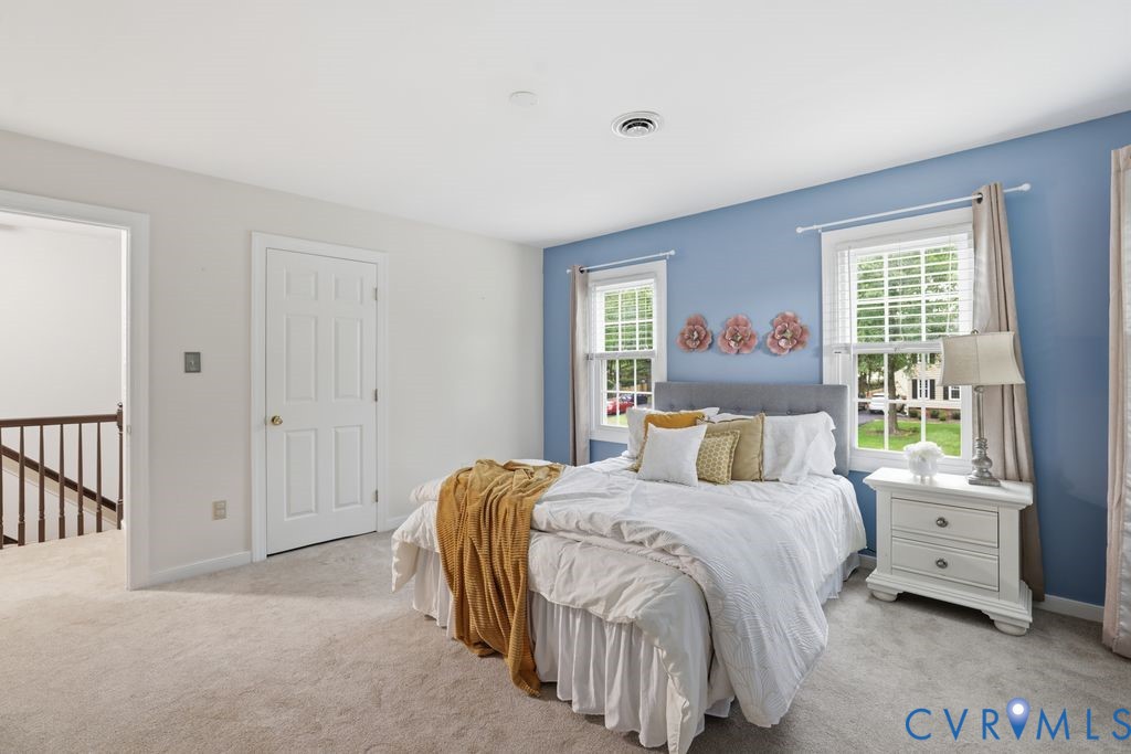 Carpeted room with a paneled door, two windows with blinds, and white trim