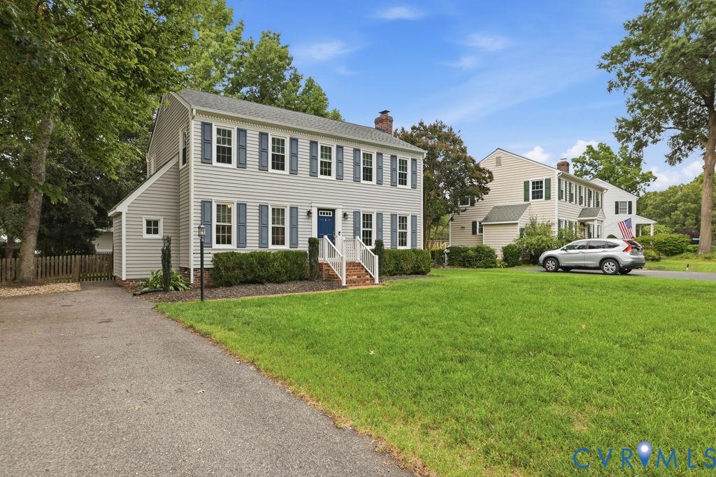 Traditional two-story residence featuring light gray siding, a prominent blue entry door, and blue window shutters