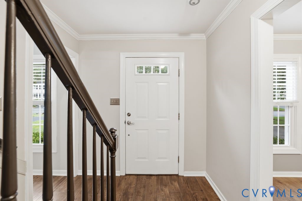 Entryway featuring a white paneled door with transom windows, wood-finish flooring, and crown molding