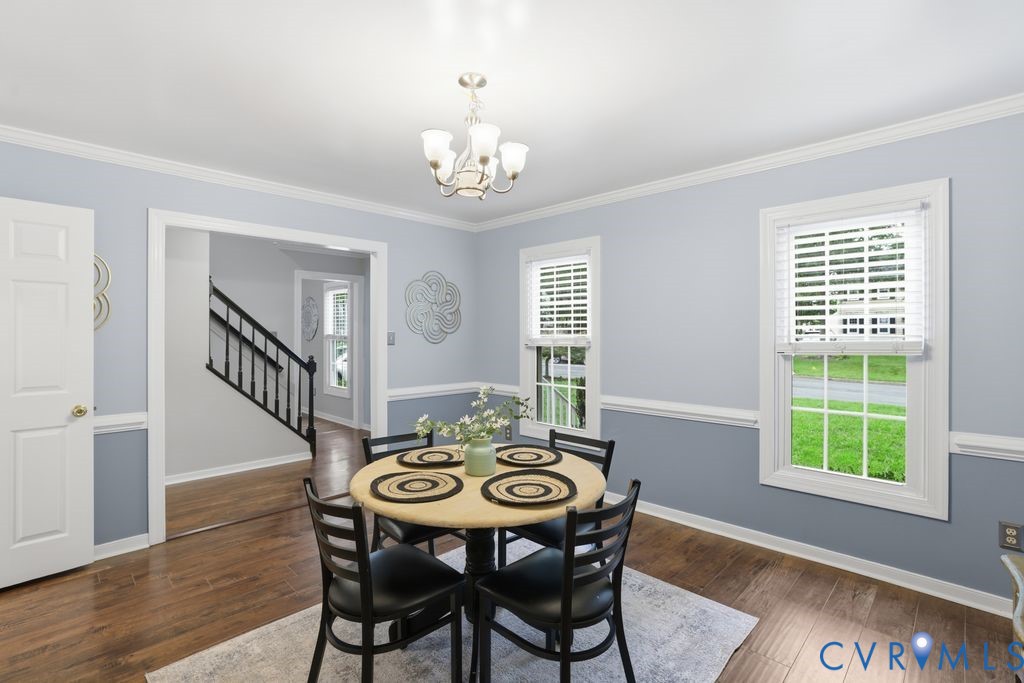 Elegant dining room featuring soft blue and gray two-tone wall treatment with chair rail molding, hardwood flooring, and abundant natural light from multi-pane windows and glass doors