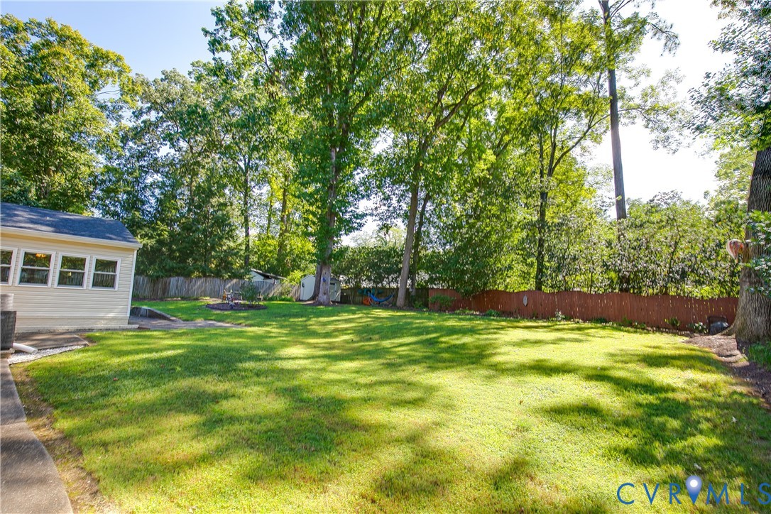 Expansive backyard featuring a manicured lawn, mature trees, and a privacy fence