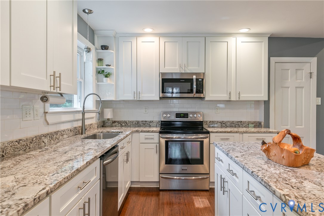 White shaker-style cabinetry with brushed nickel hardware, light-toned stone countertops, and stainless steel appliances