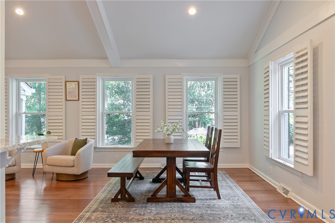 Wood-finish flooring, white plantation shutters, vaulted ceiling with exposed beams, and recessed lighting
