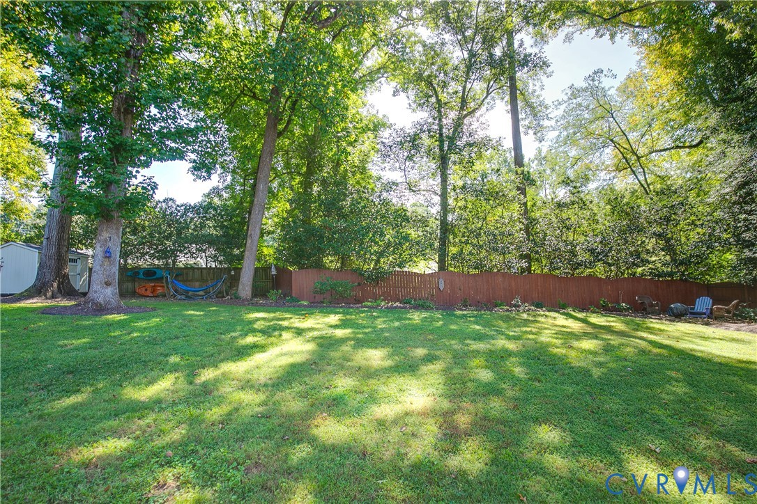Expansive green lawn with mature trees and a wood privacy fence