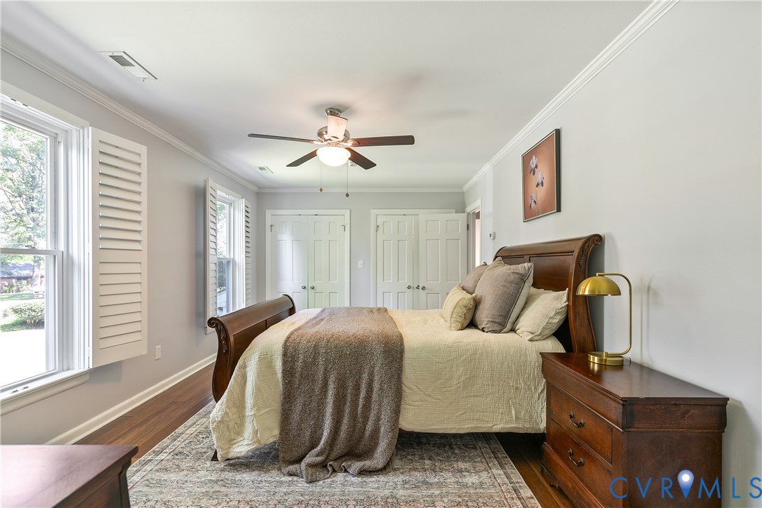 Hardwood-finish flooring, crown molding, double windows with plantation shutters, ceiling fan, and double panel doors