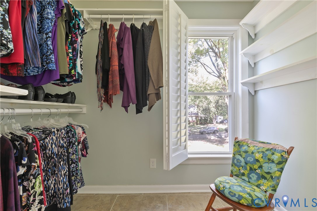 Custom closet organization system, multiple shelving units, plantation shutters, large window, and tile flooring
