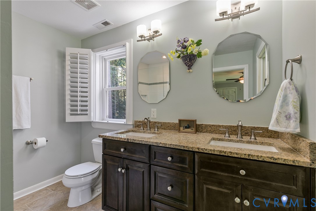 Dual vanity with integrated sinks, granite countertop, and dark wood-finish cabinetry