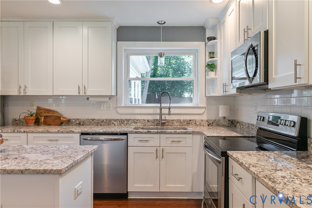 White shaker cabinetry, stainless steel appliances, granite countertops, subway tile backsplash, and wood-finish flooring