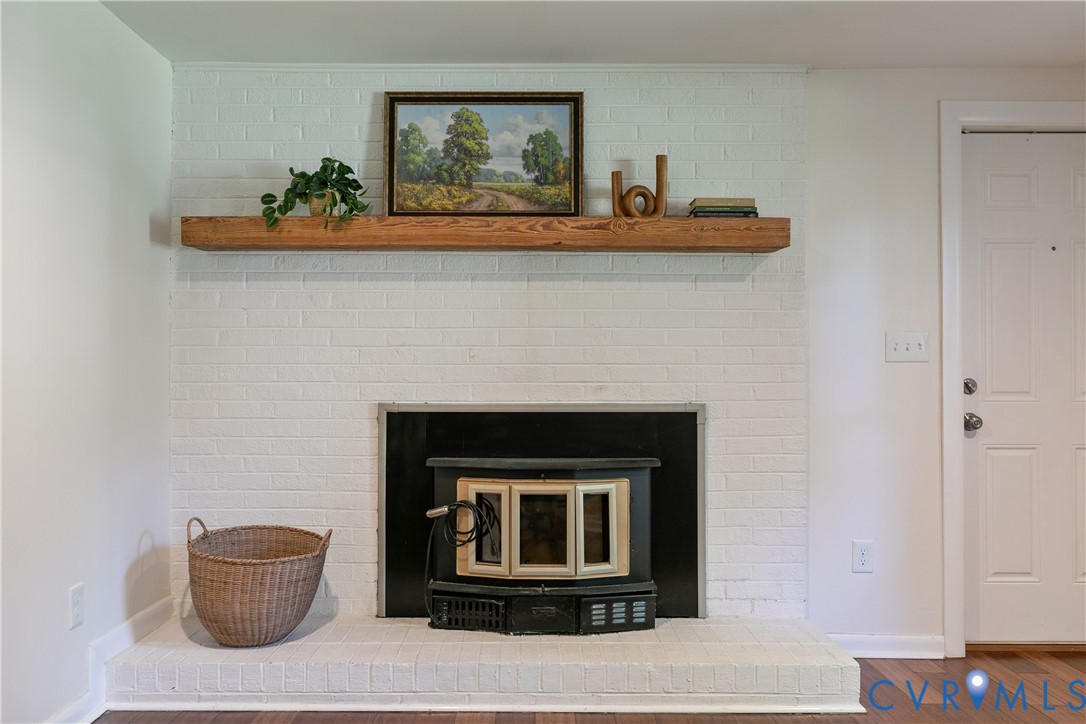 Painted brick fireplace with a wood-burning insert and a rustic wooden mantel