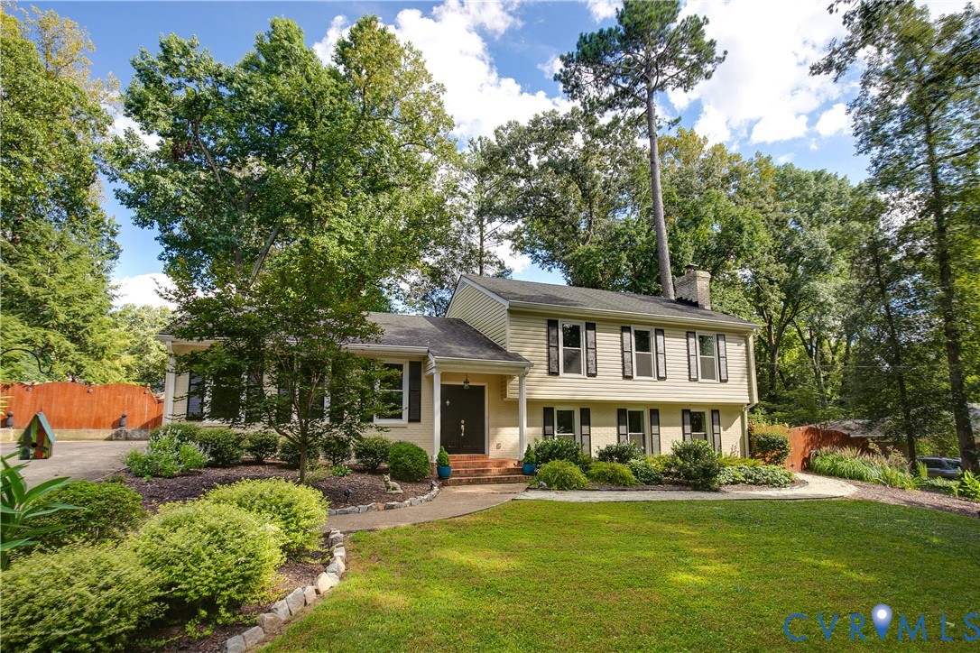 Two-story residence featuring light-colored siding, black window shutters, a prominent chimney, and a dark front door
