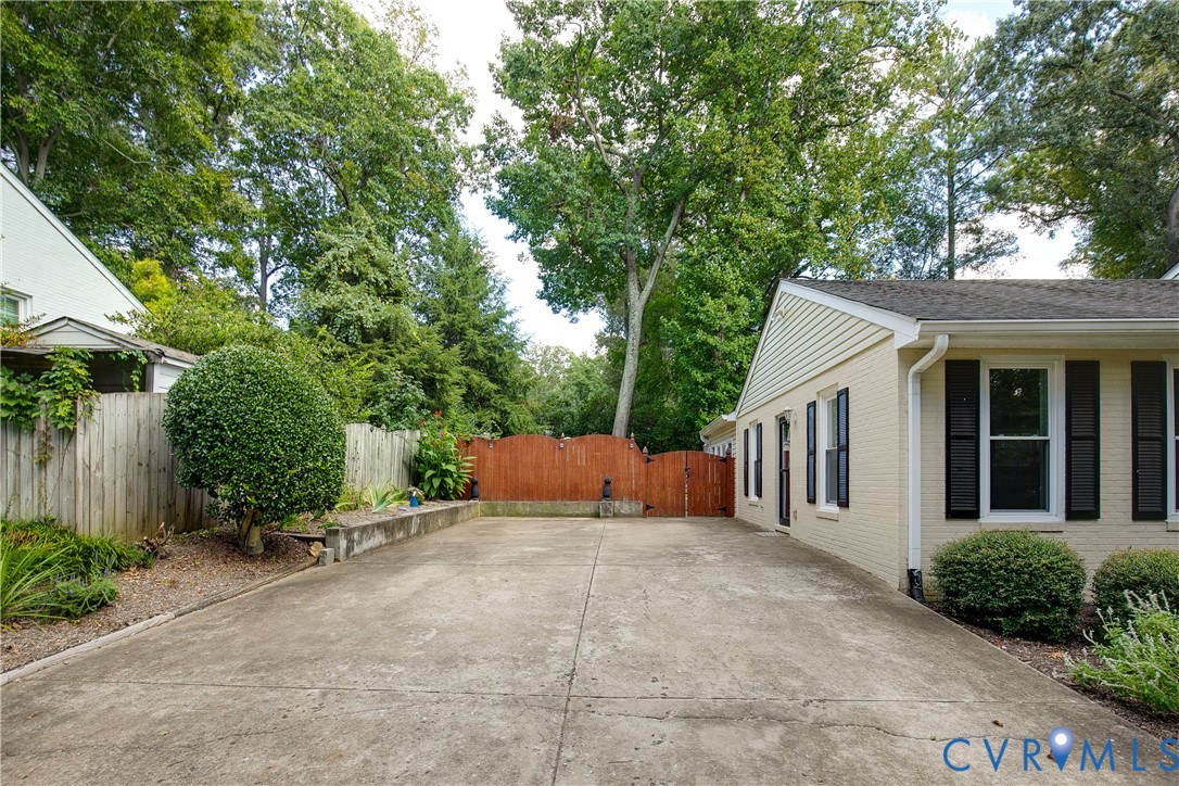 Paved driveway with a side-gabled roofline and light-colored brick exterior