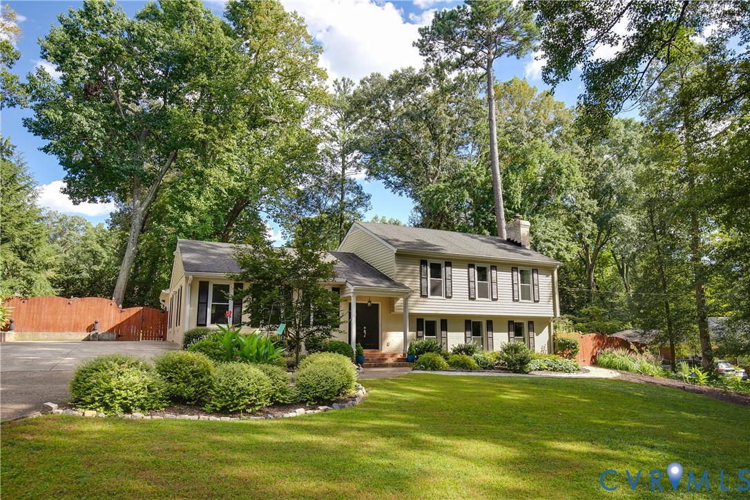Two-story residence with a light-colored siding exterior, dark shutters, and a dark shingle roof