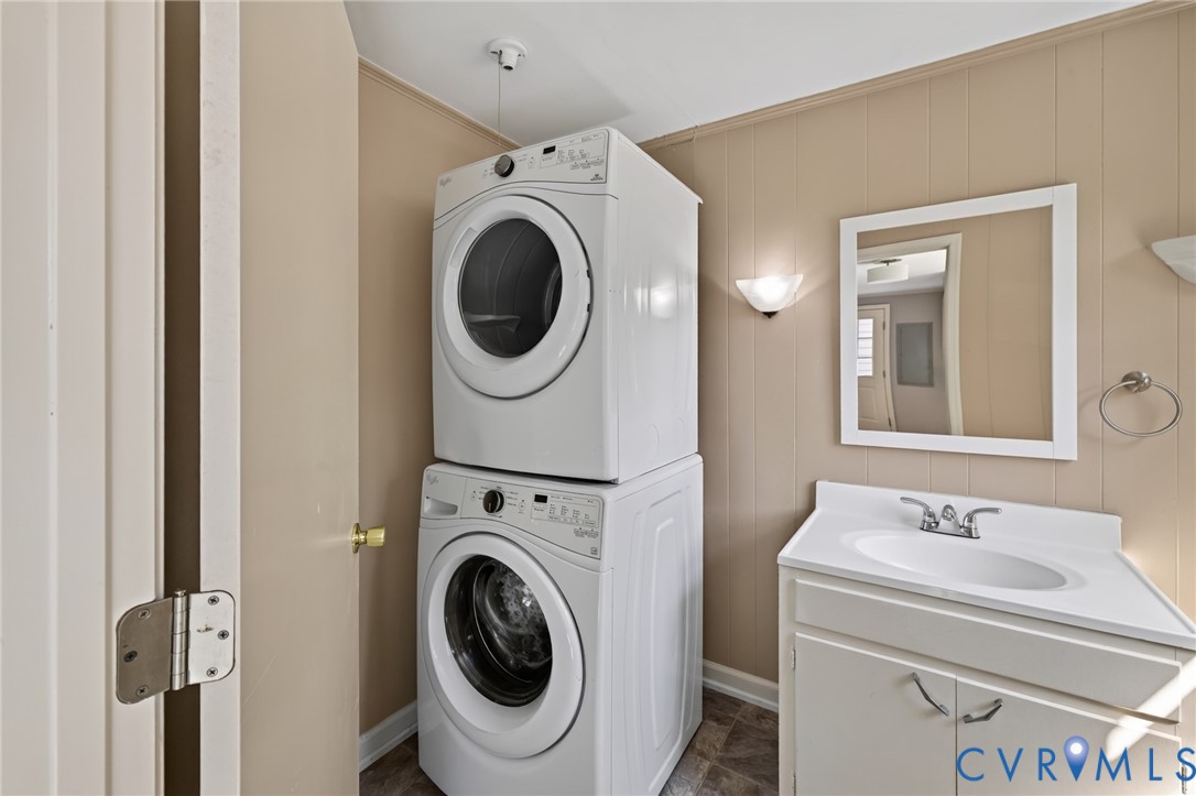 Stacked washer and dryer, vanity with integrated sink, wall-mounted mirror, and wall sconces