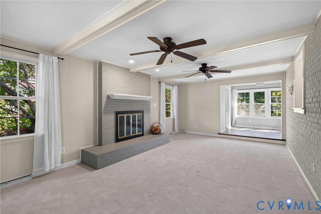 Recessed lighting, exposed ceiling beams, and a brick fireplace with a hearth