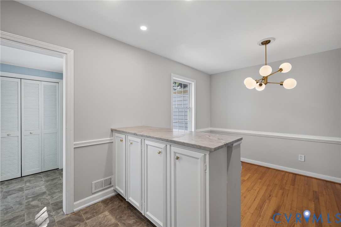 Built-in cabinetry with a stone-finish countertop, wood-finish flooring, recessed lighting, and a modern chandelier