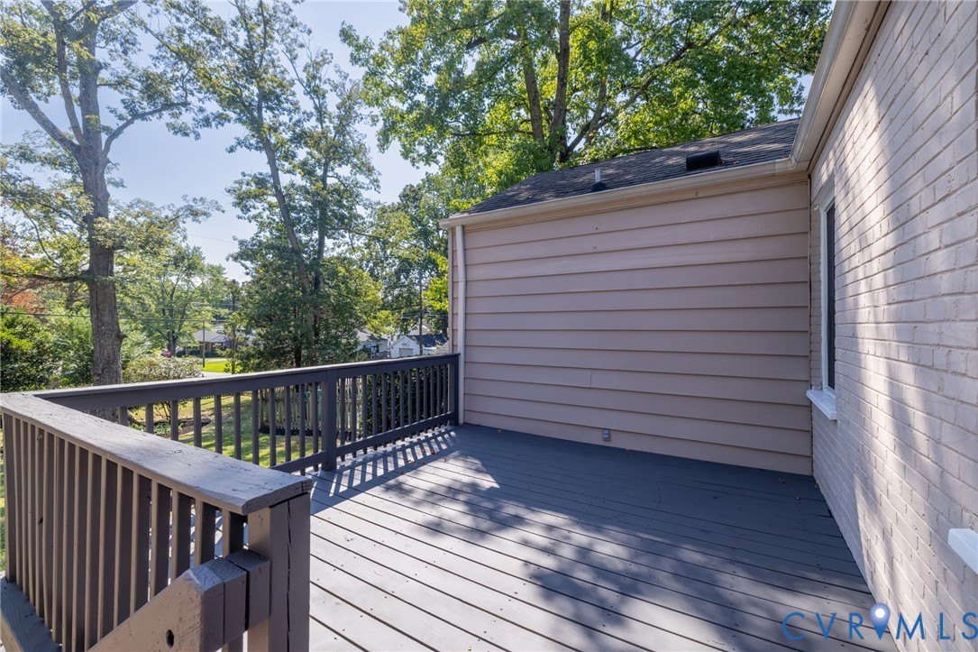 Expansive outdoor deck with wood railings, a horizontal siding exterior, and a painted brick facade