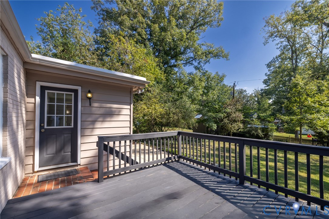 Expansive outdoor deck with dark railing, offering a brick landing and a door with divided lites