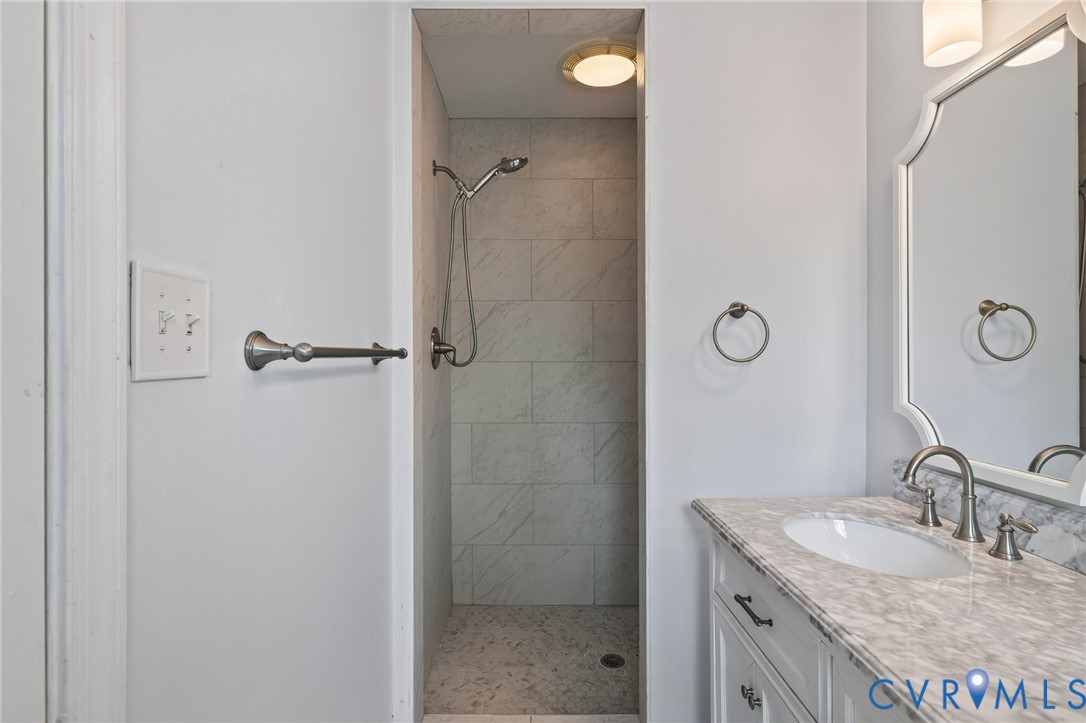 Vanity with an oval undermount sink, stone countertop, and brushed nickel faucet
