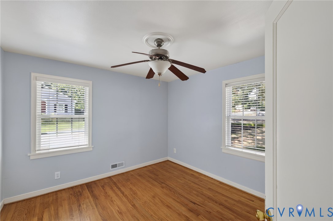 Wood-finish flooring, two window openings, ceiling fan, and crown molding