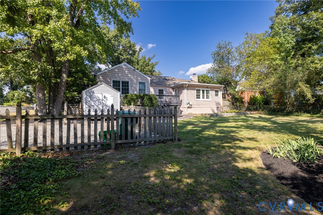 Expansive backyard with a manicured lawn, established trees, and a picket fence