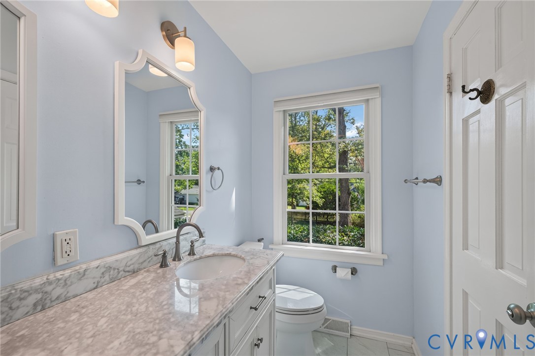 White wood-framed vanity with a built-in sink, stone countertop, and dark-finish faucet