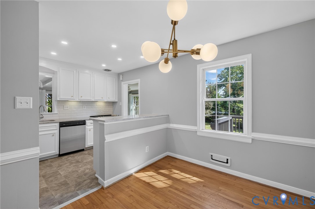 Hardwood flooring, modern chandelier, double-hung window, crown molding, and stainless steel dishwasher