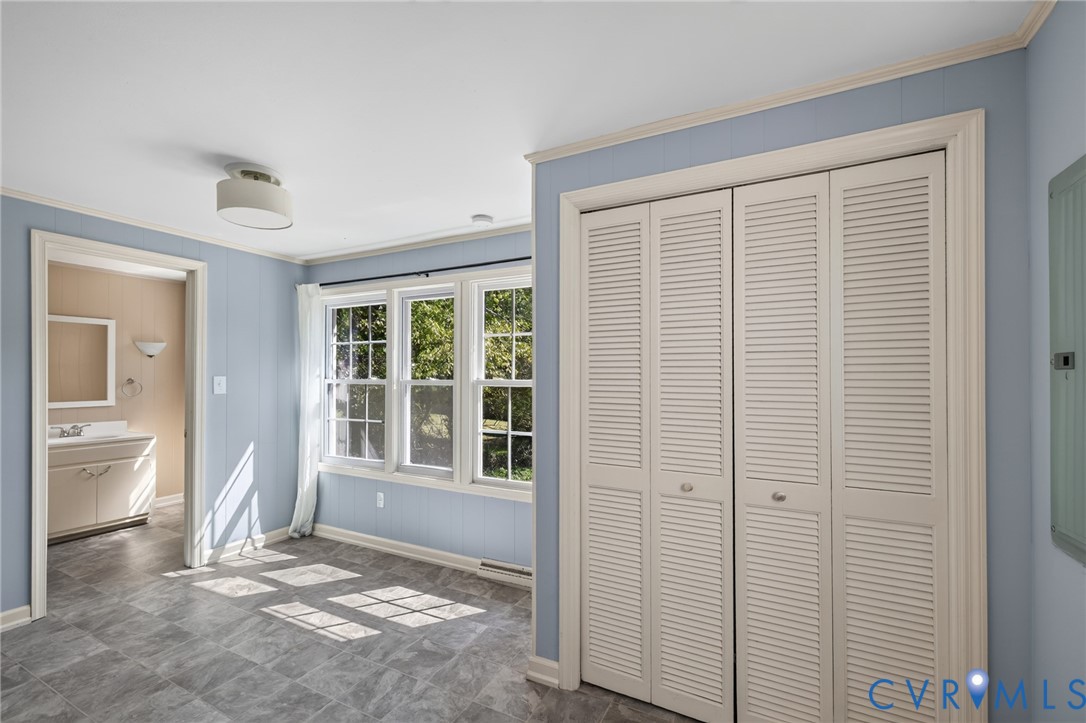 Recessed windows with grid patterns, louvered bi-fold closet doors, wall paneling, and a flush mount ceiling fixture