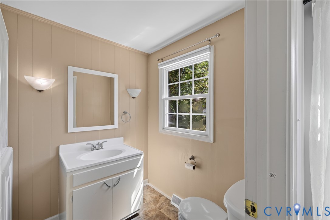 White vanity with integrated sink, wall-mounted mirror, and sconce lighting