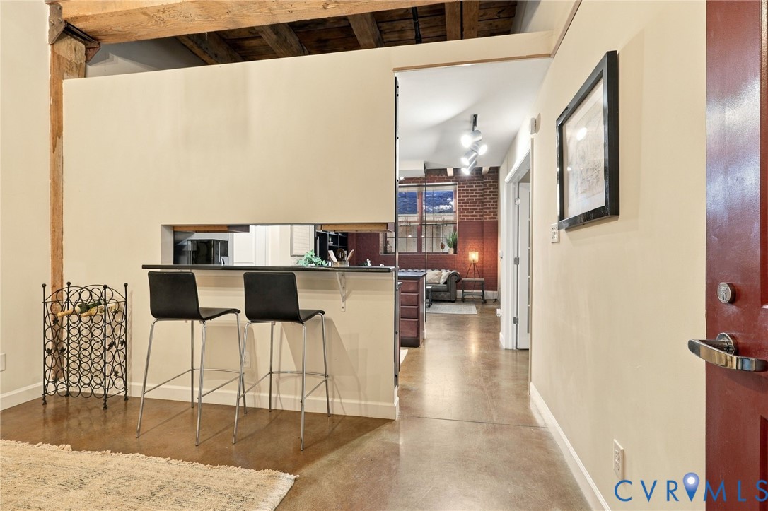 Exposed wood beam ceiling and polished concrete flooring extend throughout the home.