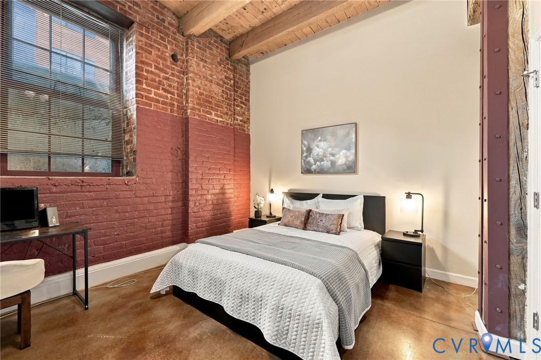 High timber ceilings extend into the primary bedroom with a large window.