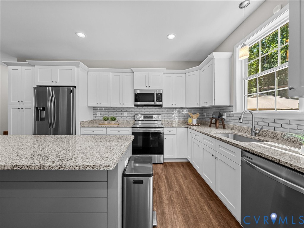 White cabinetry, stainless steel appliances, wood-finish flooring, undermount sink, and granite countertops