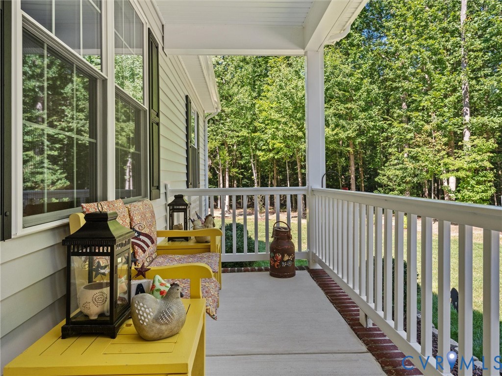 Covered front porch with white railings, a concrete surface, and white siding
