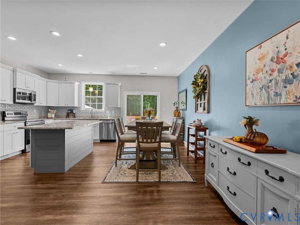 Kitchen featuring stainless steel appliances, white cabinetry, a tile backsplash, and an island with a countertop