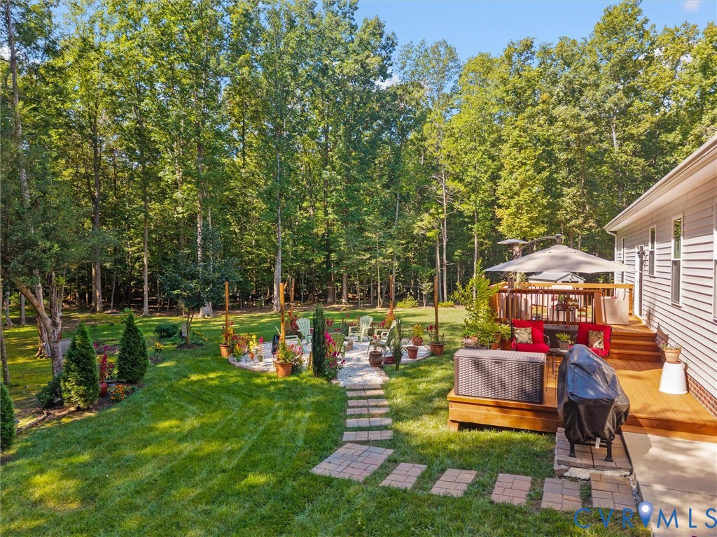 Expansive backyard with a manicured lawn, stone pathway, and mature trees