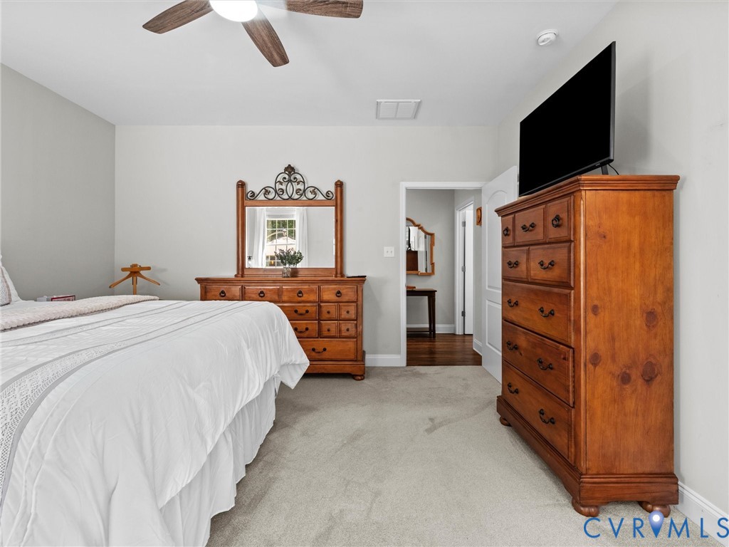 Carpeted flooring, vaulted ceiling, ceiling fan with integrated lighting, and a white paneled door