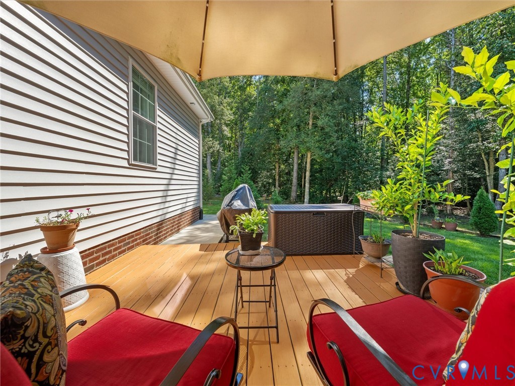 Deck with wood-finish flooring, white siding exterior, and a green lawn