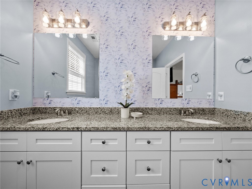 Dual vanity with white shaker-style cabinetry, undermount sinks, and speckled countertops