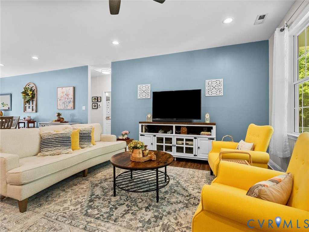 Recessed ceiling lighting, wood-finish flooring, and a large window with white curtains