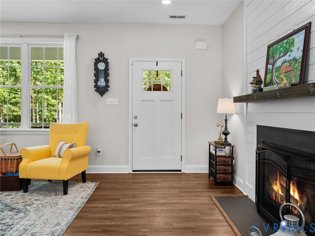 White entry door with a divided light window, wood-finish flooring, recessed lighting, and a fireplace with a wood mantel