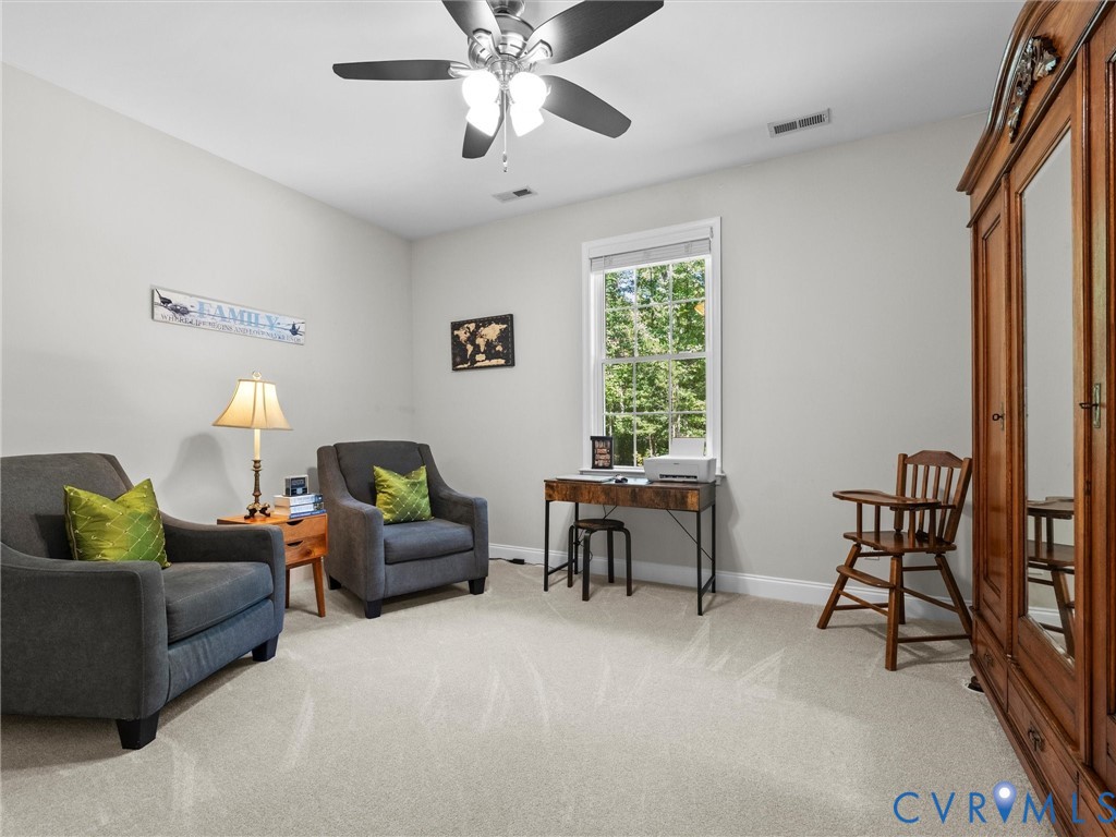 Ceiling fan with integrated lighting, window with exterior landscape, light-toned wall paint, neutral carpeting, and white trim