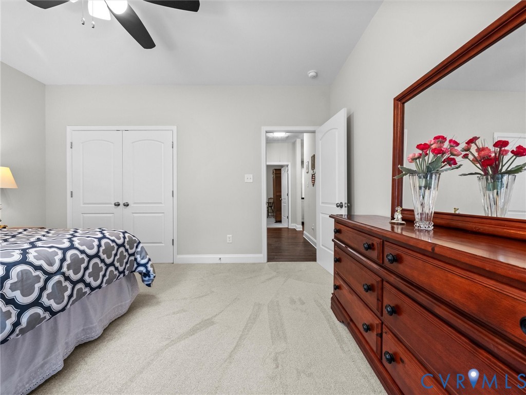 Plush carpeting, light gray wall color, white double bi-fold closet doors, and a ceiling fan with light fixture