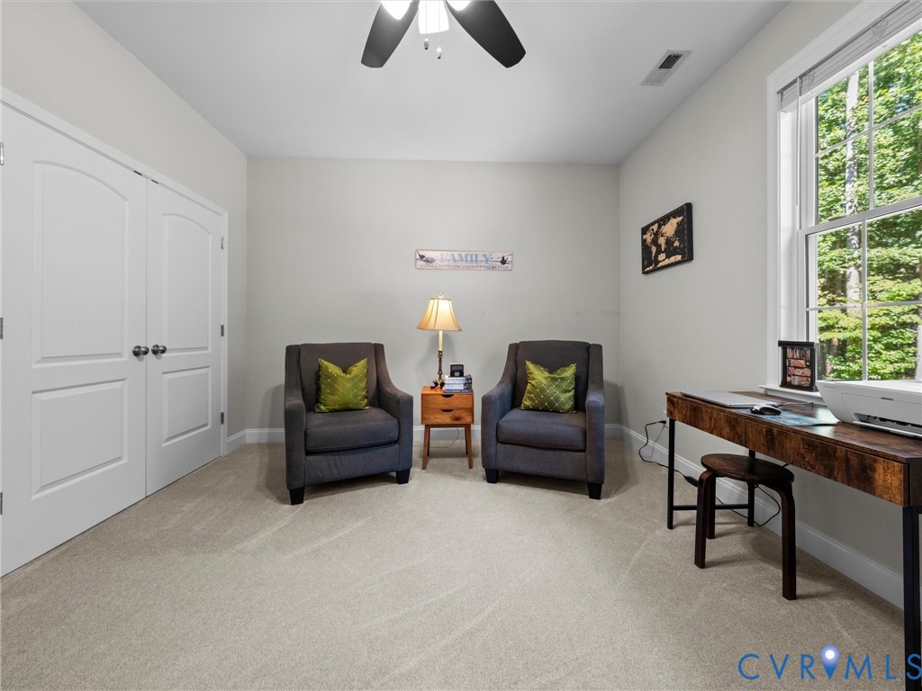 Arched panel closet doors, ceiling fan, carpet flooring, and a large window
