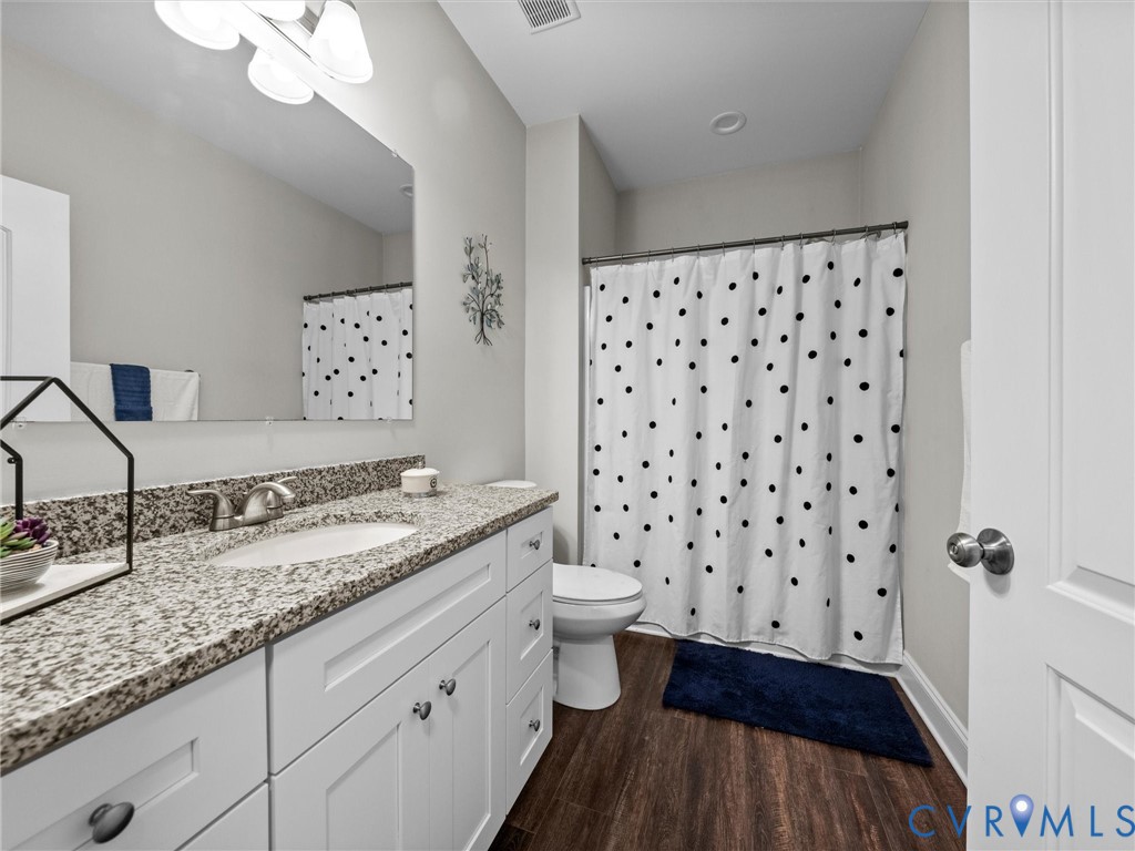 White shaker-style vanity with a granite-style countertop and undermount sink