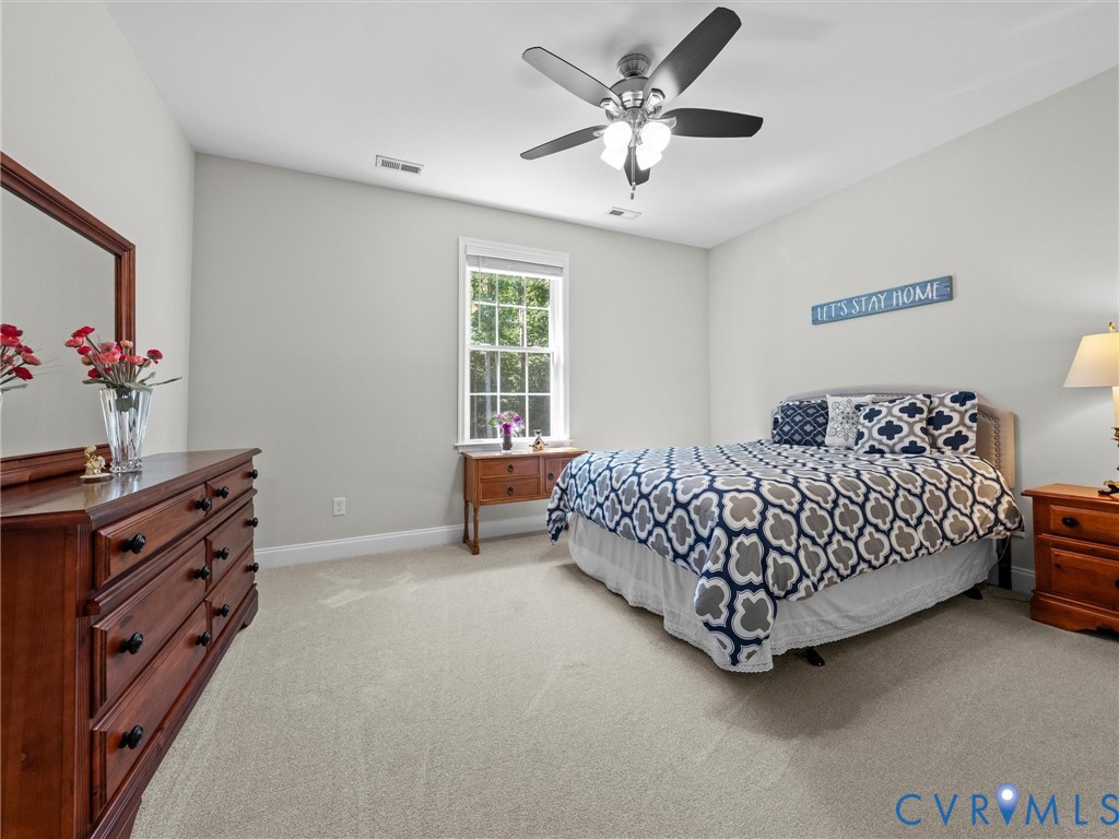 Neutral tone wall paint, light-colored carpeting, window with natural light, ceiling fan with integrated lighting, recessed lighting
