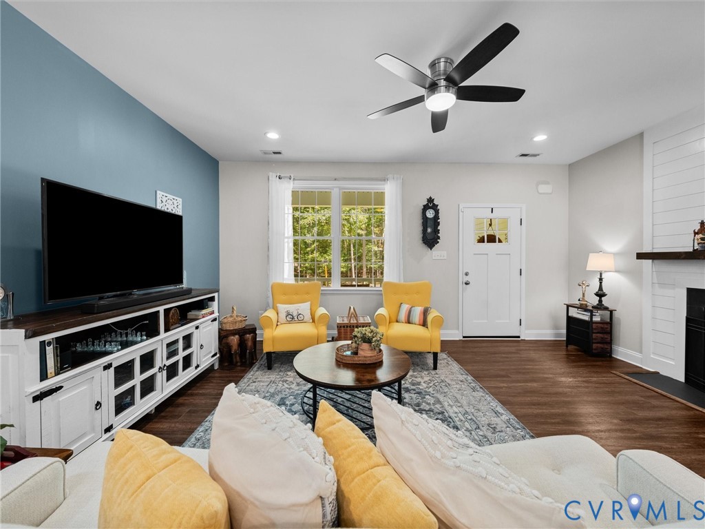 Recessed lighting, wood-finish flooring, ceiling fan, fireplace with shiplap accent, and a paneled entry door with glass inserts