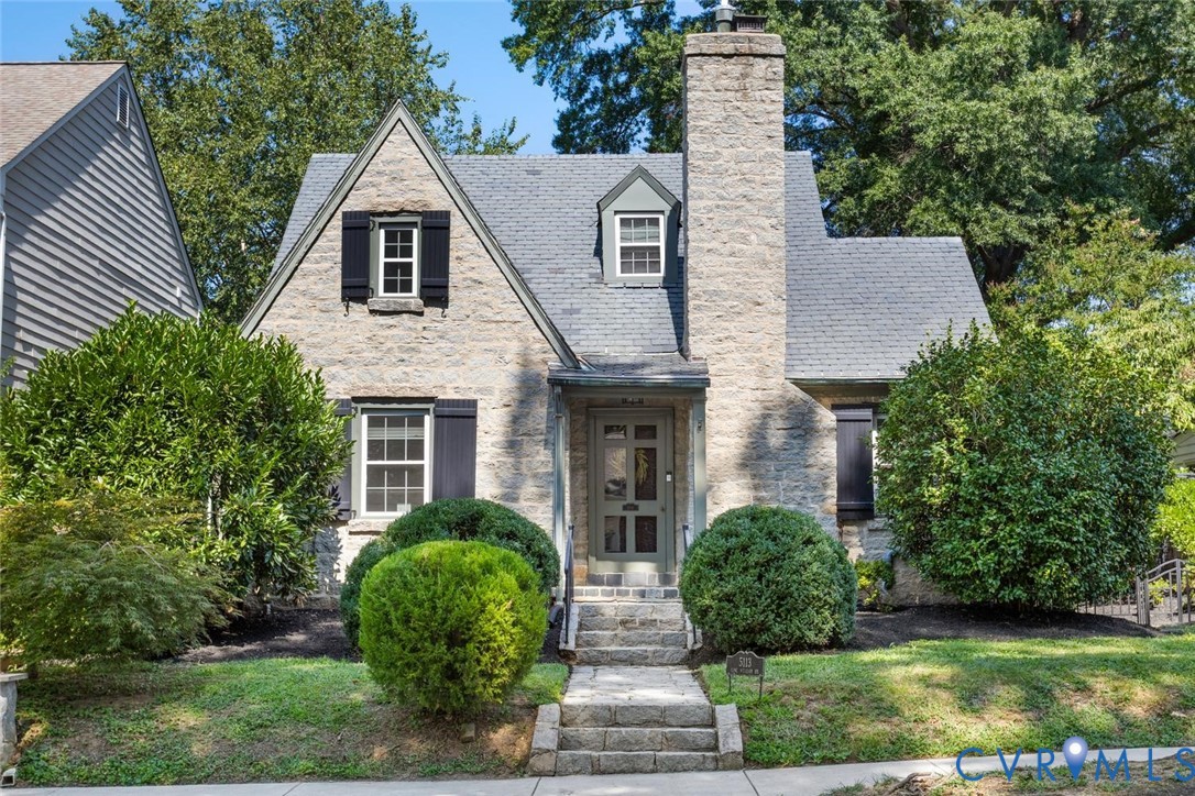 Stone exterior facade with a prominent chimney, gabled roofline, and dormer window