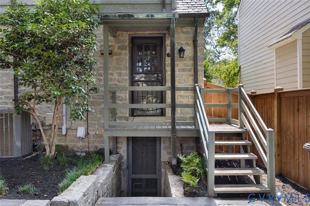 Stone exterior with a wooden deck and staircase